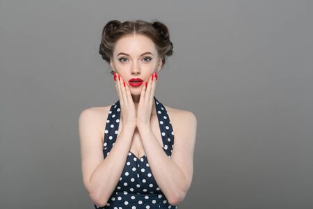 Pin up woman portrait. Beautiful retro female in polka dot dress with red lips. Studio shot.の写真素材