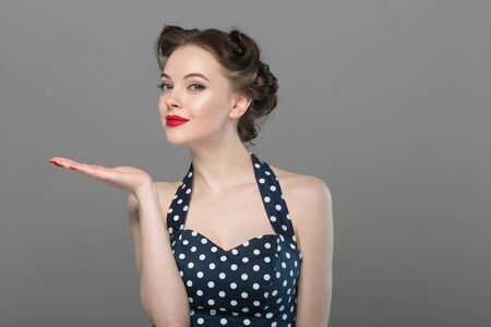 Pin up woman portrait. Beautiful retro female in polka dot dress with red lips. Studio shot.の写真素材