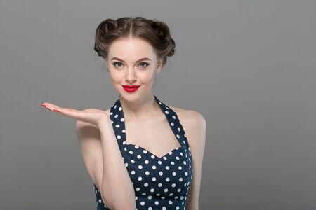 Pin up woman portrait. Beautiful retro female in polka dot dress with red lips. Studio shot.の写真素材