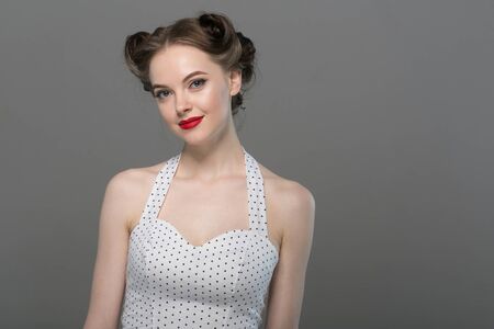 Pin up woman portrait. Beautiful retro female in polka dot dress with red lips. Studio shot.の写真素材