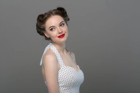 Pin up woman portrait. Beautiful retro female in polka dot dress with red lips. Studio shot.の写真素材