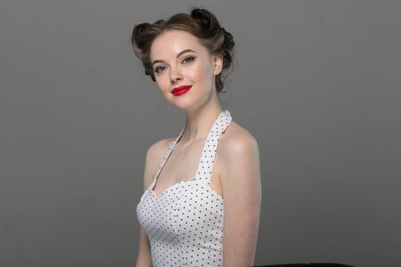 Pin up woman portrait. Beautiful retro female in polka dot dress with red lips. Studio shot.の写真素材