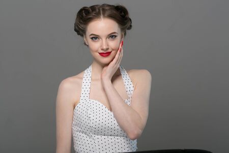 Pin up woman portrait. Beautiful retro female in polka dot dress with red lips. Studio shot.の写真素材