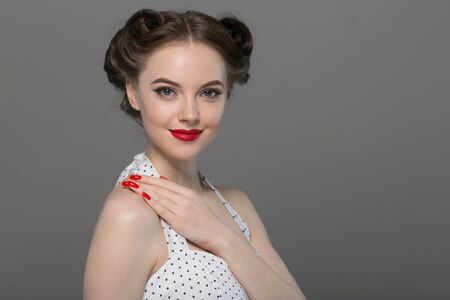 Pin up woman portrait. Beautiful retro female in polka dot dress with red lips. Studio shot.の写真素材
