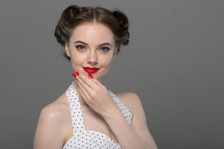 Pin up woman portrait. Beautiful retro female in polka dot dress with red lips. Studio shot.の写真素材