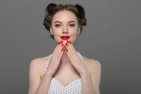 Pin up woman portrait. Beautiful retro female in polka dot dress with red lips. Studio shot.の写真素材