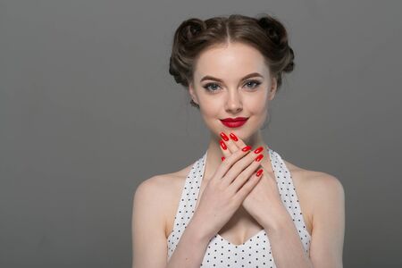 Pin up woman portrait. Beautiful retro female in polka dot dress with red lips. Studio shot.の写真素材