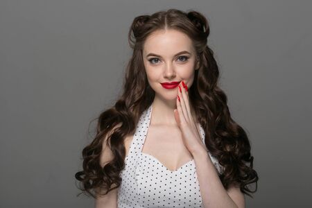 Pin up woman portrait. Beautiful retro female in polka dot dress with red lips. Studio shot.の写真素材
