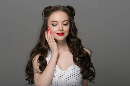 Pin up woman portrait. Beautiful retro female in polka dot dress with red lips. Studio shot.の写真素材