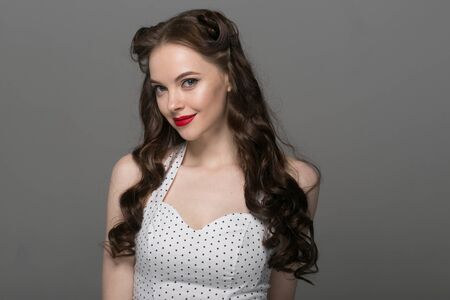 Pin up woman portrait. Beautiful retro female in polka dot dress with red lips. Studio shot.の写真素材