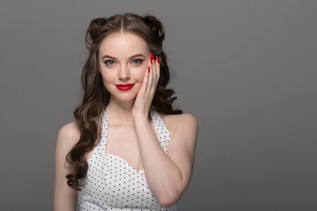 Pin up woman portrait. Beautiful retro female in polka dot dress with red lips. Studio shot.の写真素材