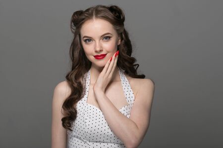 Pin up woman portrait. Beautiful retro female in polka dot dress with red lips. Studio shot.の写真素材