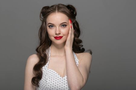 Pin up woman portrait. Beautiful retro female in polka dot dress with red lips. Studio shot.の写真素材