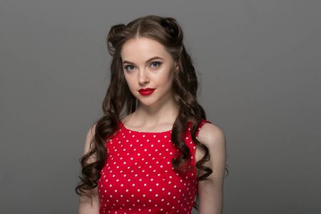 Pin up woman portrait. Beautiful retro female in polka dot dress with red lips. Studio shot.の写真素材