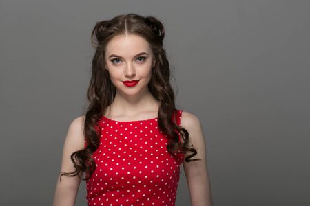 Pin up woman portrait. Beautiful retro female in polka dot dress with red lips. Studio shot.の写真素材