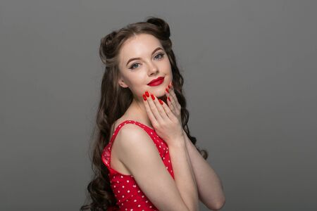 Pin up woman portrait. Beautiful retro female in polka dot dress with red lips. Studio shot.の写真素材