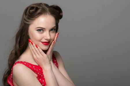 Pin up woman portrait. Beautiful retro female in polka dot dress with red lips. Studio shot.の写真素材