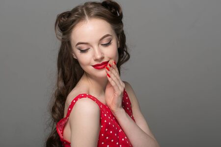 Pin up woman portrait. Beautiful retro female in polka dot dress with red lips. Studio shot.の写真素材