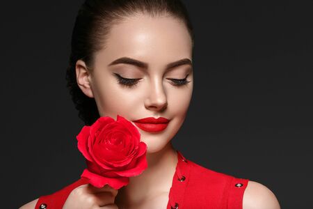 Beauty woman with rose flower beautiful curly hair and lips. Studio shot.の写真素材