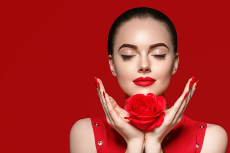 Beauty woman with rose flower beautiful curly hair and lips. Studio shot.の写真素材