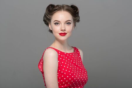 Pin up woman portrait. Beautiful retro female in polka dot dress with red lips. Studio shot.の写真素材
