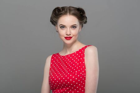 Pin up woman portrait. Beautiful retro female in polka dot dress with red lips. Studio shot.の写真素材