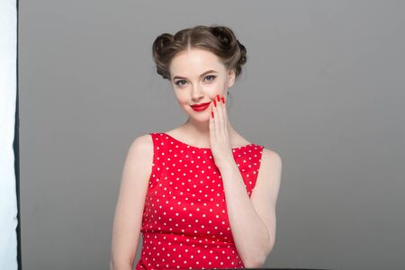 Pin up woman portrait. Beautiful retro female in polka dot dress with red lips. Studio shot.の写真素材