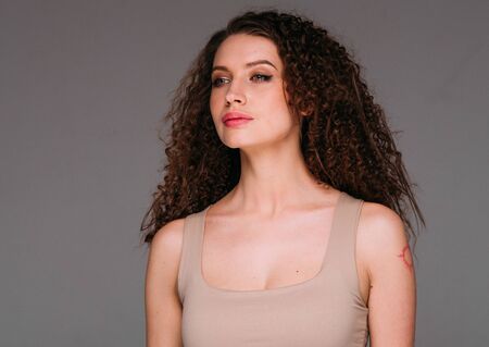 Curly hair woman beautiful beauty portrait, female glamour face with long brunette hairstyle. Studio shot.の写真素材