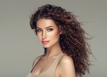 Curly hair woman beautiful beauty portrait, female glamour face with long brunette hairstyle. Studio shot.の写真素材