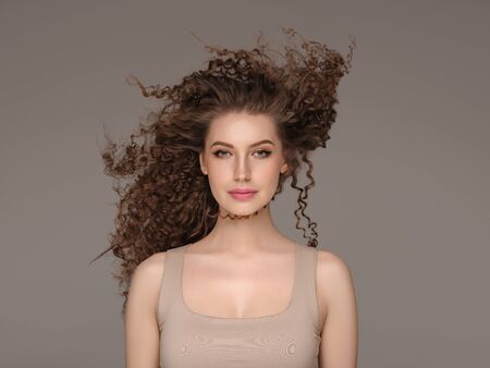 Curly hair woman beautiful beauty portrait, female glamour face with long brunette hairstyle. Studio shot.の写真素材