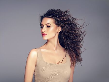 Curly hair woman beautiful beauty portrait, female glamour face with long brunette hairstyle. Studio shot.の写真素材