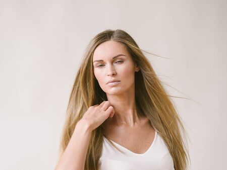 Beautiful woman natural portrait girl with long blonde hair over white gray wall. Studio shot.の写真素材
