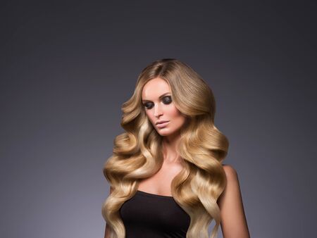 Blond woman long hair curly natural fashion makeup. Studio shot.の写真素材