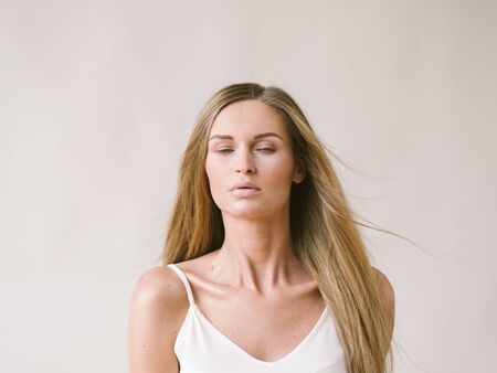 Beautiful woman natural portrait girl with long blonde hair over white gray wall. Studio shot.の写真素材