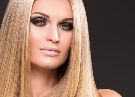 Hair beautiful long blond hairstyle woman fashion makeup healthy skin and hair black background. Studio shot.の写真素材