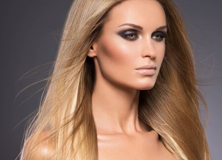 Hair beautiful long blond hairstyle woman fashion makeup healthy skin and hair black background. Studio shot.の写真素材