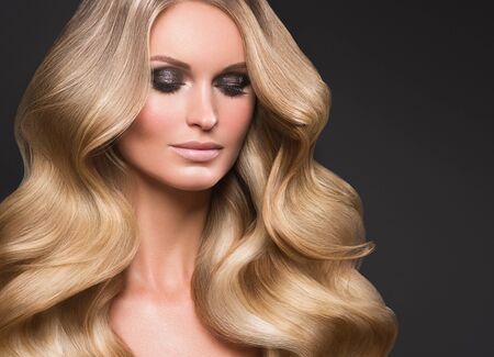 Blond woman long hair curly natural fashion makeup. Studio shot.の写真素材
