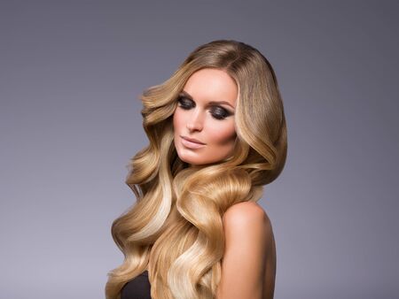 Blond woman long hair curly natural fashion makeup. Studio shot.の写真素材