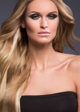 Blond woman long hair curly natural fashion makeup. Studio shot.の写真素材