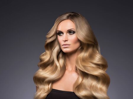 Blond woman long hair curly natural fashion makeup. Studio shot.の写真素材