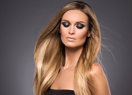 Hair beautiful long blond hairstyle woman fashion makeup healthy skin and hair black background. Studio shot.の写真素材