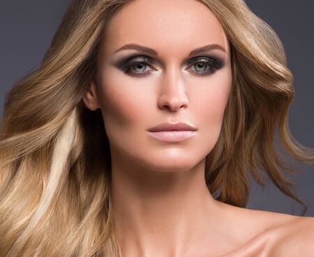 Blond woman long hair curly natural fashion makeup. Studio shot.の写真素材