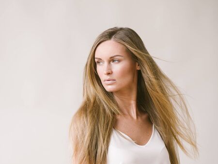 Beautiful woman natural portrait girl with long blonde hair over white gray wall. Studio shot.の写真素材