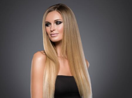 Hair beautiful long blond hairstyle woman fashion makeup healthy skin and hair black background. Studio shot.の写真素材