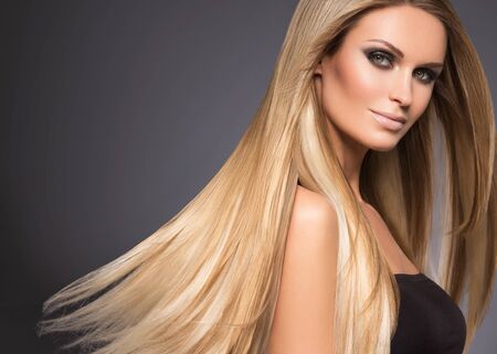 Hair beautiful long blond hairstyle woman fashion makeup healthy skin and hair black background. Studio shot.の写真素材