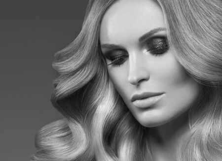 Healthy curly hair woman long blonde hairstyle female. Studio shot. Monochrome. Gray. Black and white.の写真素材