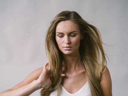 Beautiful woman natural portrait girl with long blonde hair over white gray wall. Studio shot.の写真素材