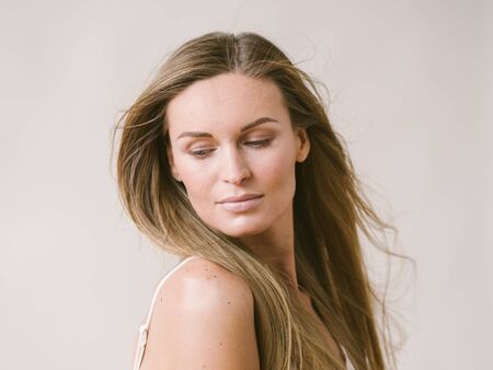 Beautiful woman natural portrait girl with long blonde hair over white gray wall. Studio shot.の写真素材