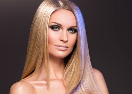 Hair beautiful long blond hairstyle woman fashion makeup healthy skin and hair black background. Studio shot.の写真素材