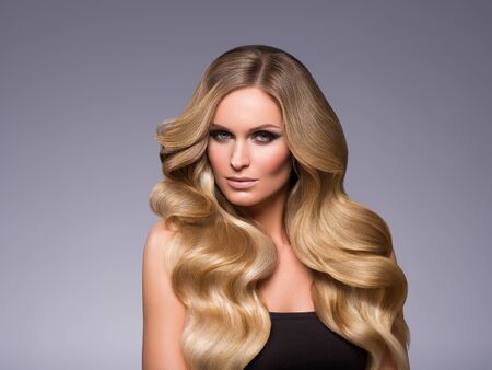 Blond woman long hair curly natural fashion makeup. Studio shot.の写真素材